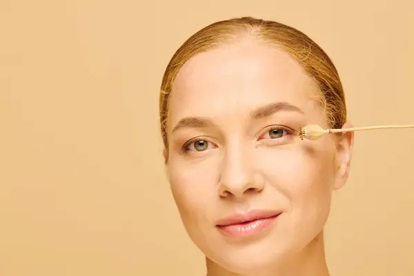 A young beautiful plus size woman gently applies skincare to her face, showcasing self care. — Stockfoto