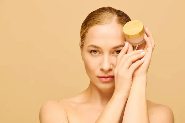 A young beautiful plus size woman presents a skincare jar while embracing her natural beauty. — Stock Photo