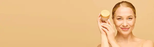 A radiant woman showcases her favorite skincare product, exuding confidence and joy. — Stock Photo