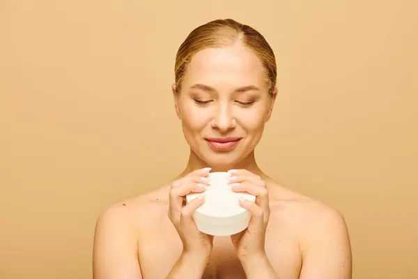 The young woman closes her eyes, savoring the soothing aroma of her skincare product. — Stock Photo