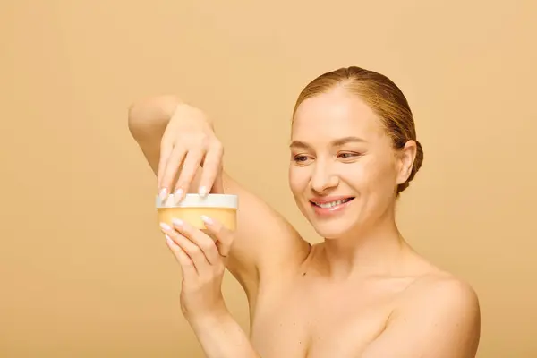 A joyful plus size woman is applying cream on her skin, radiating happiness and confidence. — Stock Photo