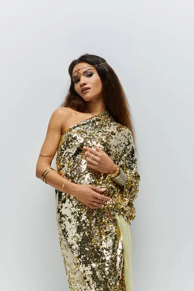 An inspiring African American woman radiates confidence in a dazzling golden dress inside a stylish studio. — Stock Photo