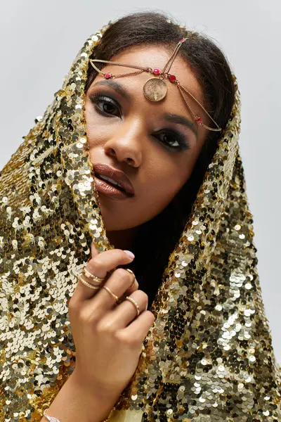 An African American goddess adorned in a shimmering golden dress captures the light in a studio setting. — Stock Photo