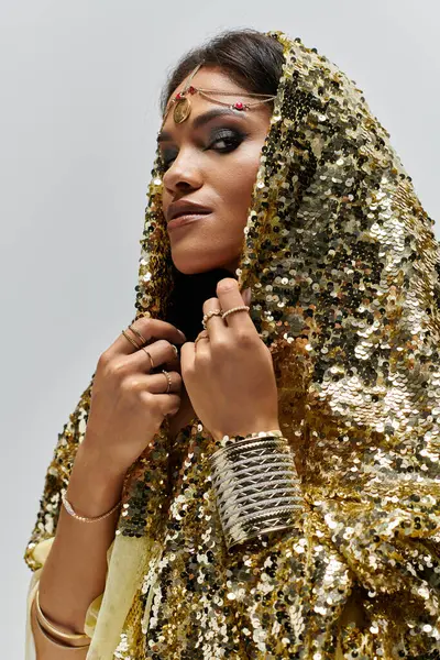 An enchanting African American goddess exudes confidence in a shimmering golden dress amidst a stylish backdrop. — Stock Photo