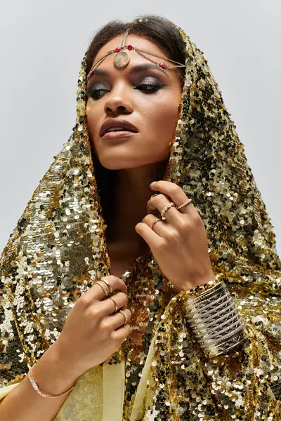 A stunning African American goddess captivates with her golden attire and striking pose in a stylish studio. — Stock Photo