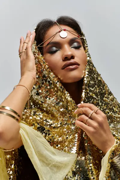 An African American goddess showcases her beauty in a shiny golden dress, radiating confidence in a studio. — Stock Photo