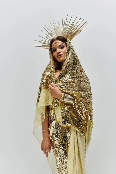 An enchanting African American goddess adorned in a radiant golden dress exudes beauty and confidence in a studio. — Stock Photo