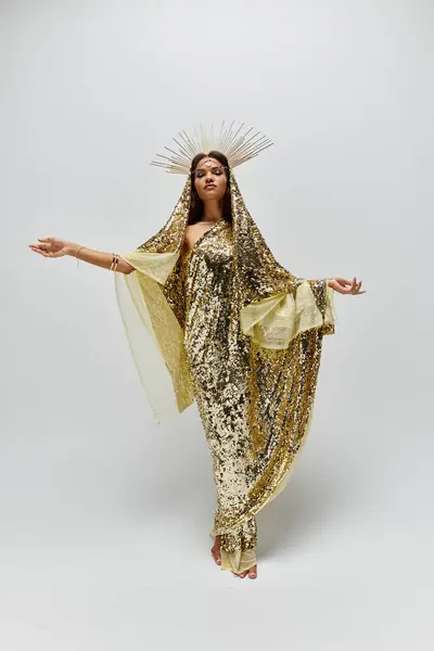 An enchanting figure adorned in a dazzling golden dress radiates beauty and elegance against a minimalist backdrop. — Stock Photo