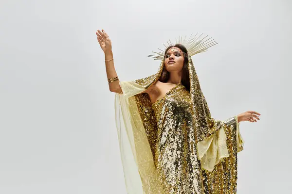 The stunning goddess in shimmering gold raises her arm elegantly against a clean backdrop, exuding confidence. — Stock Photo