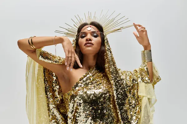 A stunning goddess poses gracefully in a shiny golden dress, showcasing elegance and strength in a refined studio. — Stock Photo