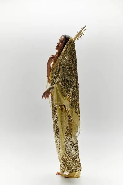 An enchanting figure adorned in a shiny golden dress captures the essence of beauty and grace in a studio. — Stock Photo