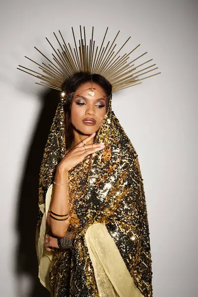 A captivating African American goddess showcases a shiny golden dress adorned with sparkling accents in a studio. — Stock Photo