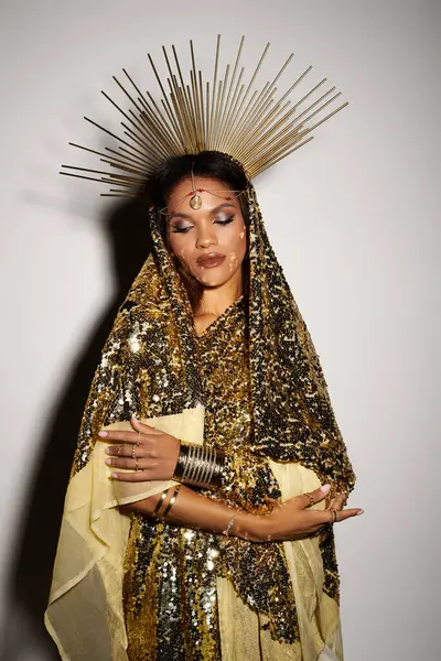 An elegant African American goddess in a shiny golden dress shines with confidence under artistic lighting. — Stock Photo