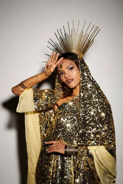 A beautiful African American goddess adorned in a sparkling golden dress poses gracefully in an elegant studio. — Stock Photo