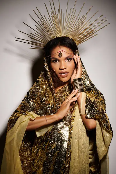 An enchanting goddess captivates with her golden dress, expressive pose, and striking studio backdrop. — Stock Photo