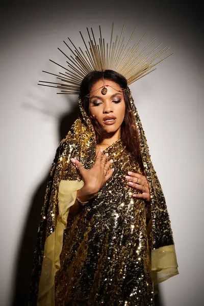 An elegant African American goddess in a shimmering golden dress radiates beauty in a serene studio atmosphere. — Stock Photo