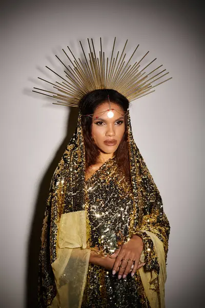 An enchanting figure in a shiny golden dress stands poised, radiating elegance with a regal headdress. — Stock Photo