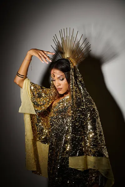 An elegant goddess in a shimmering golden dress captures the spotlight in a stylish studio environment. — Stock Photo