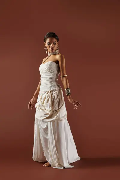 An enchanting African American woman dons a pearl necklace and white attire, exuding grace against a warm backdrop. — Stock Photo