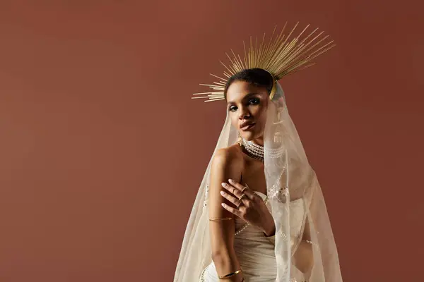 A stunning African American woman captures attention in a white gown with a pearl necklace against a brown backdrop. — Stock Photo