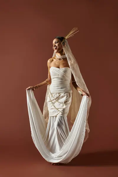 A stunning African American woman exudes grace in a flowing white dress, adorned with pearls, showcasing her elegance. — Stock Photo