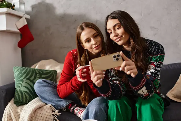 Two friends enjoy the holiday spirit, sharing laughter and warmth in cozy sweaters while celebrating at home. — Stock Photo