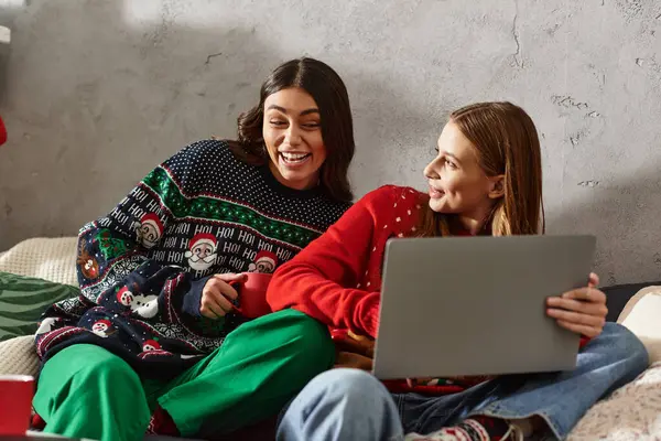 Deux amis rient et partagent la joie ensemble tout en célébrant la saison des fêtes à la maison en tenue confortable. — Photo de stock