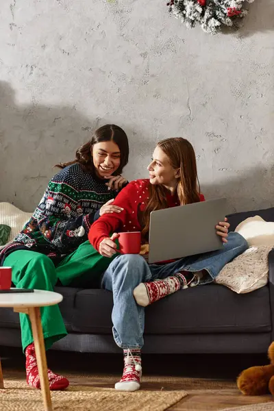 Two girlfriends relax in comfy sweaters, celebrating Christmas and New Year with warmth and joy at home. — Stockfoto