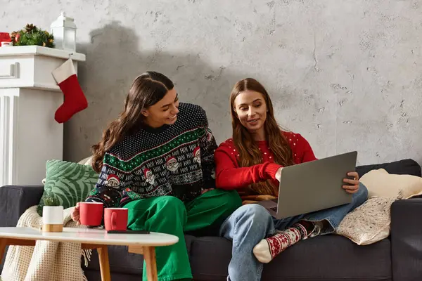 Two friends in cozy sweaters enjoy a joyful moment together, sharing holiday cheer in their warm living room. — Stockfoto