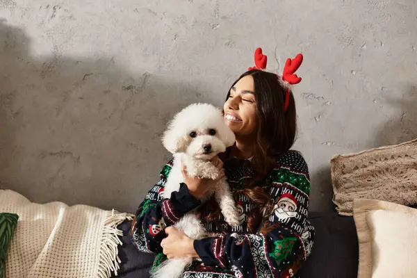 A young woman in festive attire shares a warm moment with her Bichon Frise, celebrating the New Year. — Stock Photo