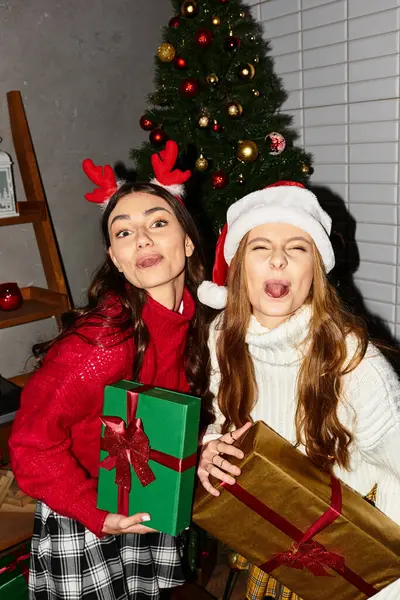 Girlfriends share joyful moments, showcasing holiday spirit with gifts and laughter near the Christmas tree. — Foto stock