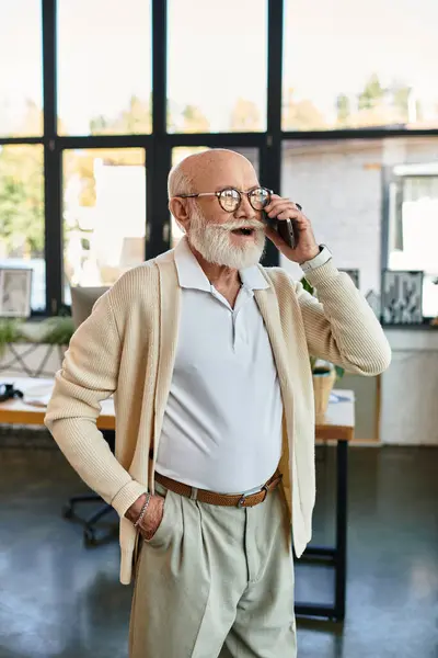 L'uomo d'affari più anziano con la barba parla caldamente mentre sta con fiducia nel suo ufficio moderno. — Foto stock