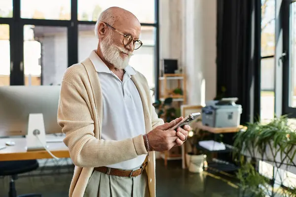 Um gerente sênior bem parecido em trajes casuais inteligentes verifica seu telefone enquanto está em um escritório brilhante. — Stock Photo