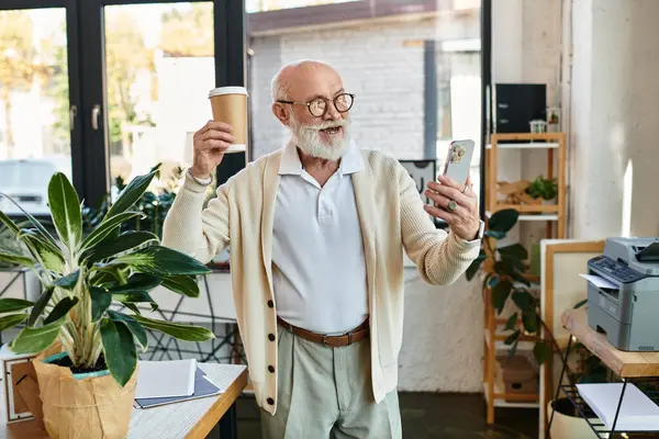 A senior businessman in smart casual attire enthusiastically engages with his smartphone while enjoying coffee. — Stock Photo
