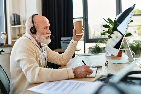 Un professionnel sénior élégant sirote du café tout en prenant des notes sur un bureau élégant, profondément concentré. — Photo de stock