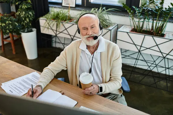 Un homme d'affaires professionnel participe à une réunion en ligne tout en sirotant un café dans un bureau élégant. — Photo de stock