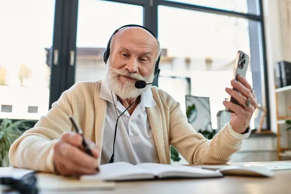 A senior businessman wearing smart casual clothes connects with colleagues, taking notes while working. — Stock Photo