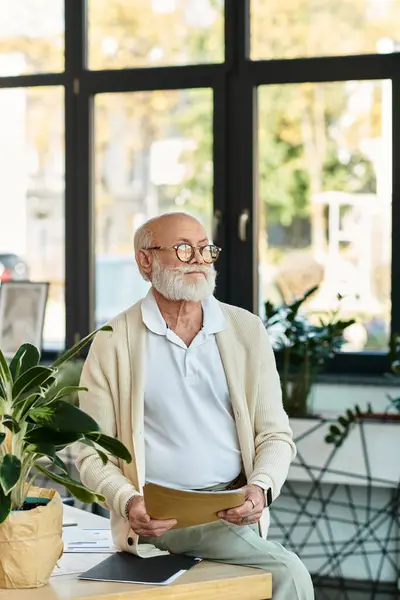 A good-looking senior manager with a beard sits thoughtfully in a stylish office, preparing for a meeting. — Stock Photo