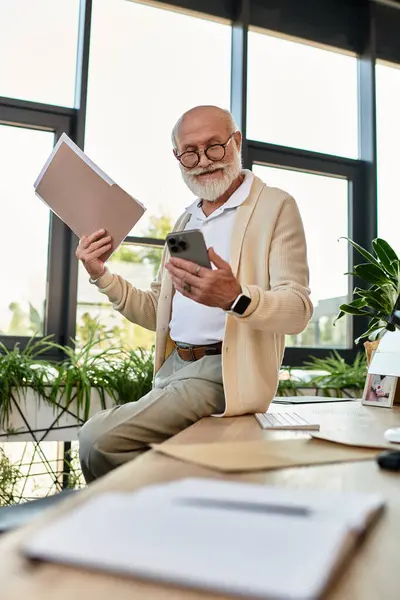 Um empresário sênior distinto revisa arquivos em seu telefone enquanto sentado em um espaço de escritório contemporâneo. — Fotografia de Stock