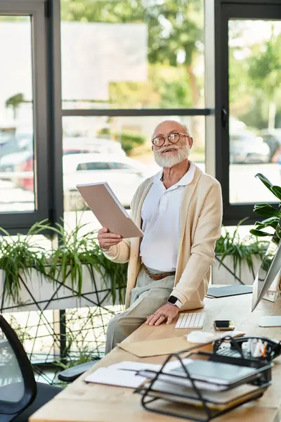 Un illustre uomo d'affari anziano sorride mentre rivede i documenti in uno spazio ufficio luminoso e moderno. — Foto stock
