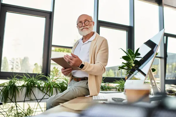 An elderly businessman with a beard discusses ideas while seated in a contemporary office setting. — Stock Photo