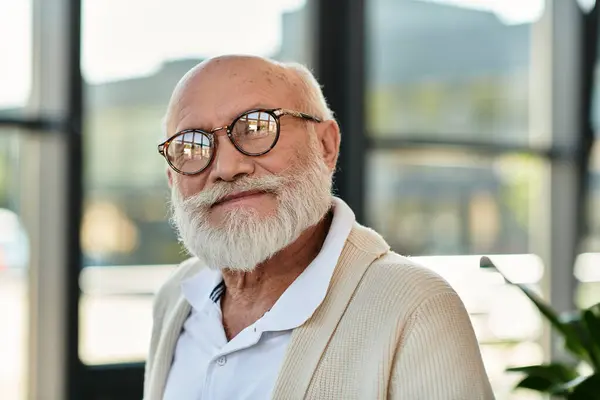 A distinguished senior businessman with a beard engages in work at his stylish office, radiating confidence. — Stock Photo