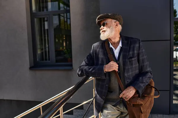 A dapper senior man in a checkered blazer enjoys the crisp autumn air near a contemporary structure. — Stock Photo