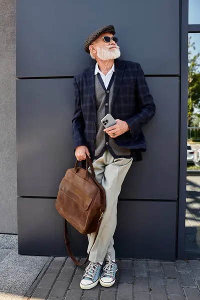 Un signore anziano alla moda si erge con fiducia vicino a una struttura contemporanea, abbracciando l'atmosfera autunnale.. — Foto stock