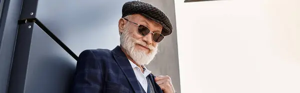 A dapper senior gentleman with a beard confidently poses outdoors in smart casual attire on a cool autumn day. — Stock Photo