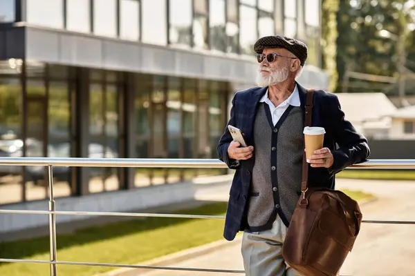 A fashionable senior man in smart casual attire holds a coffee cup while standing by a contemporary building. — Stock Photo
