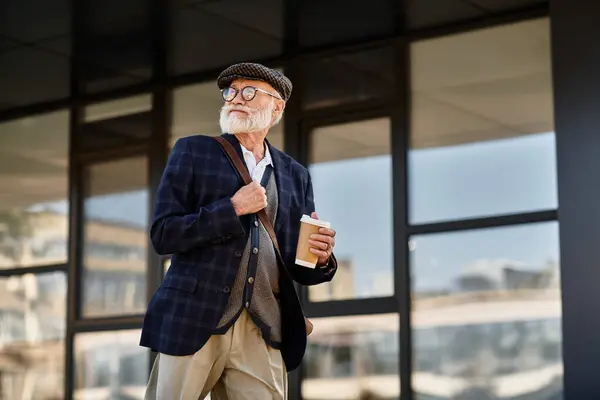 A fashionable senior man strolls confidently in smart casual attire, savoring a warm beverage. — Stock Photo