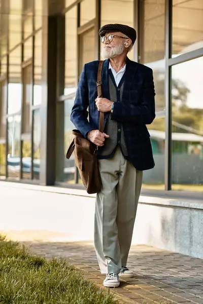 A fashionable senior man strolls confidently near a contemporary building during autumn, exuding charisma. — Stock Photo