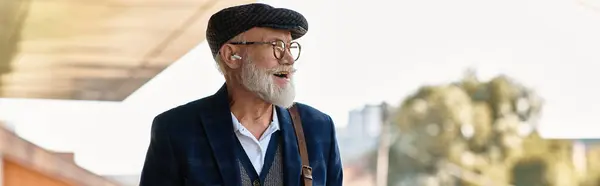 Un signore anziano alla moda passeggia davanti a una struttura contemporanea, abbracciando l'atmosfera autunnale. — Foto stock