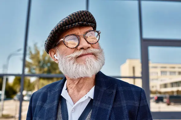 A fashionable senior gentleman stands confidently outdoors, showcasing his autumn attire and charming smile. — Stock Photo